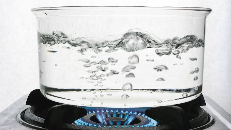 Water boiling in a clear container on a gas burner.