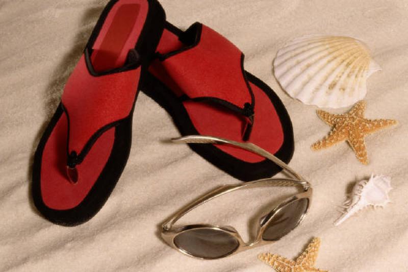 Flip flops next to sunglasses and seashell, oyster shell and star fish in white sand